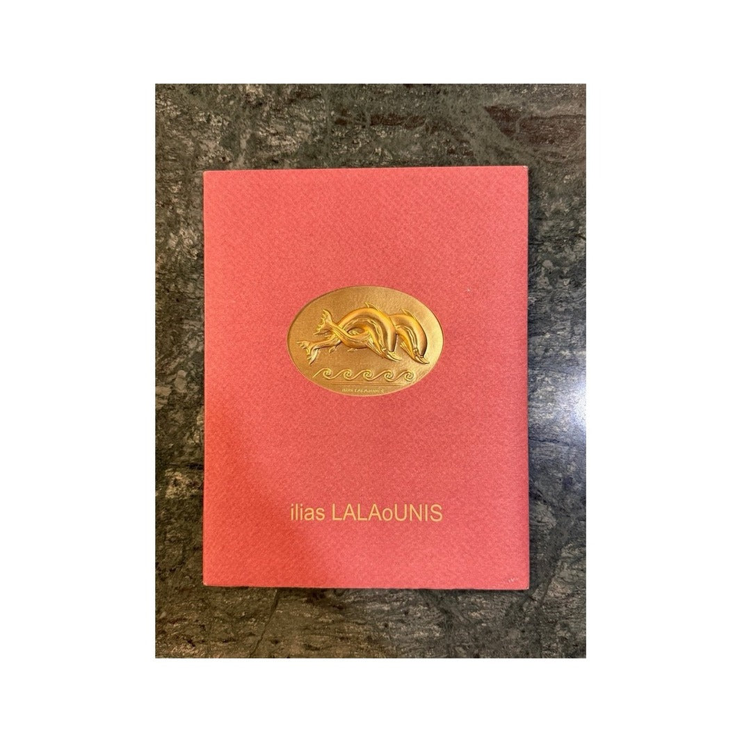 Tarjeta roja Ilias LALAoUNIS con placa dorada ovalada en relieve de delfines
