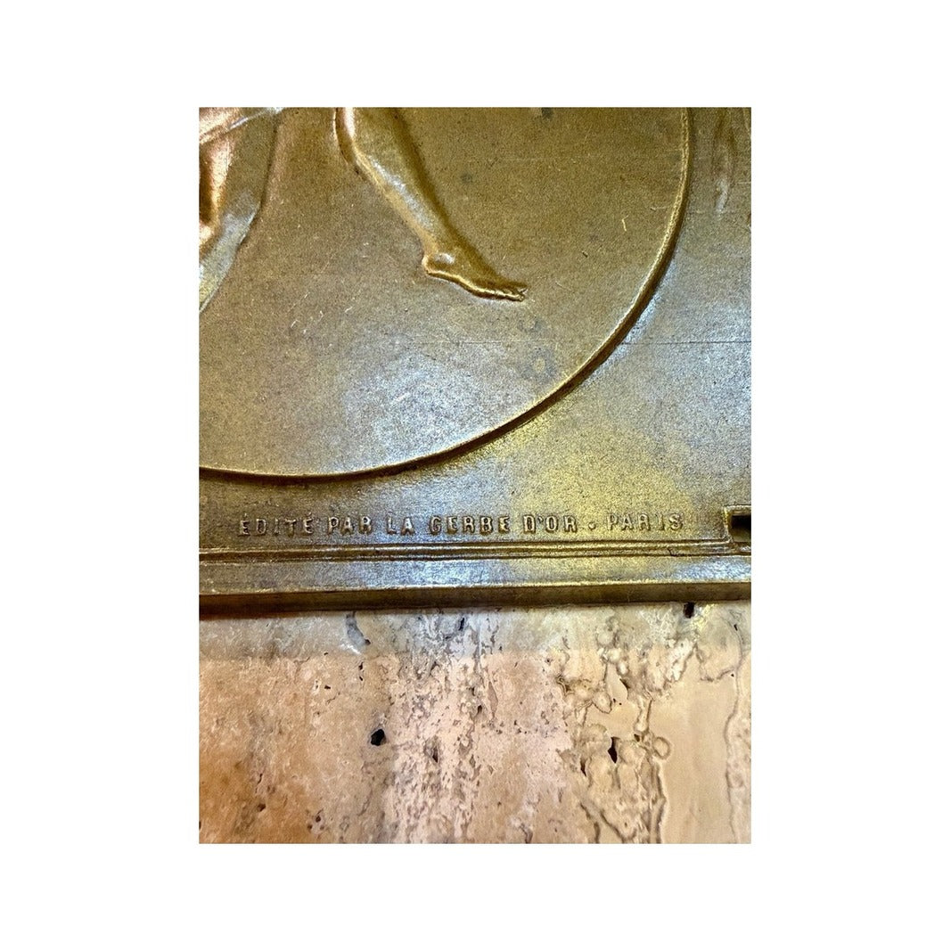 Detalle del relieve de la bailarina y edición parisina en la plaqueta de bronce