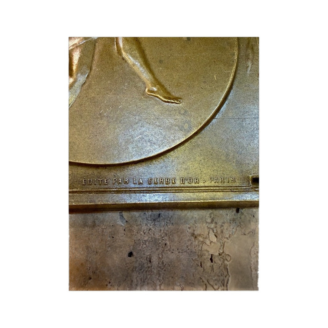 Detalle del relieve de la bailarina y edición parisina en la plaqueta de bronce