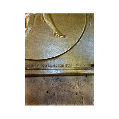Detalle del relieve de la bailarina y edición parisina en la plaqueta de bronce
