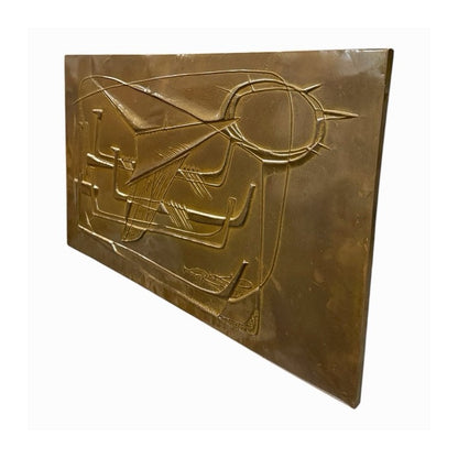Vista oblicua del panel mid-century de metal dorado con relieve geométrico y composición de barcos estilizados