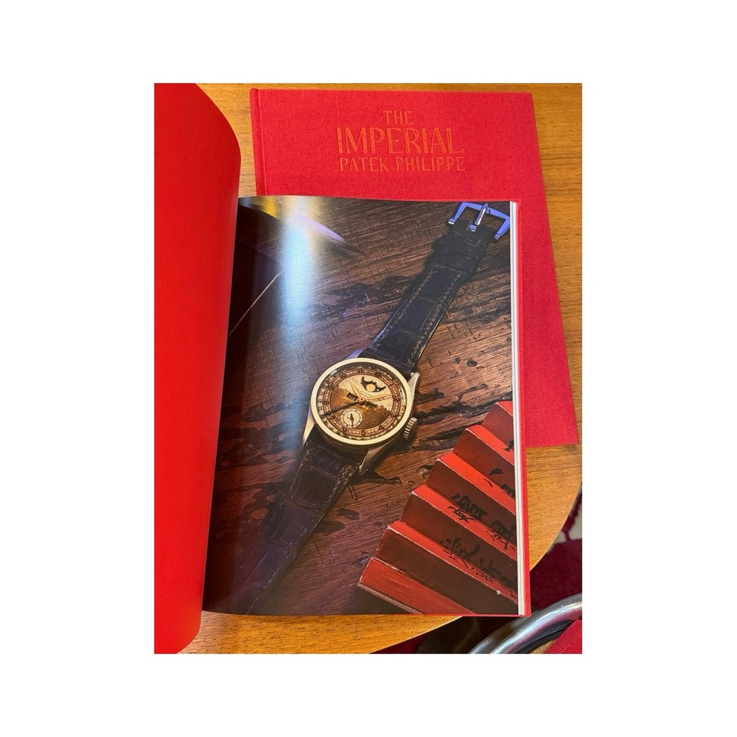 Catálogo The Imperial Patek Philippe abierto con fotografía de reloj Patek Philippe sobre mesa de madera