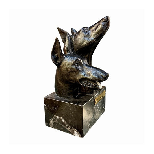 Escultura de bronce de dos cabezas de dóberman sobre base de mármol negro