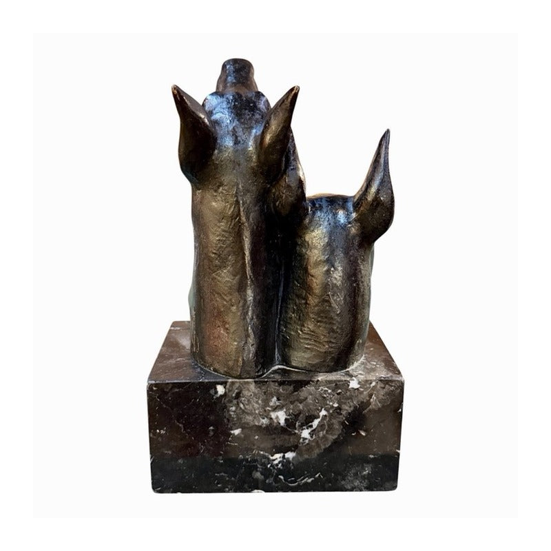 Escultura de bronce de dos cabezas de dóberman sobre base rectangular de mármol, vista desde atrás y de lado