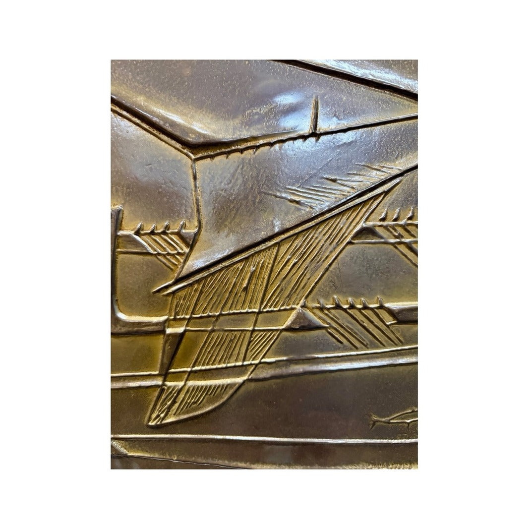 Detalle del barco abstracto en metal dorado repujado con líneas geométricas y textura martillada