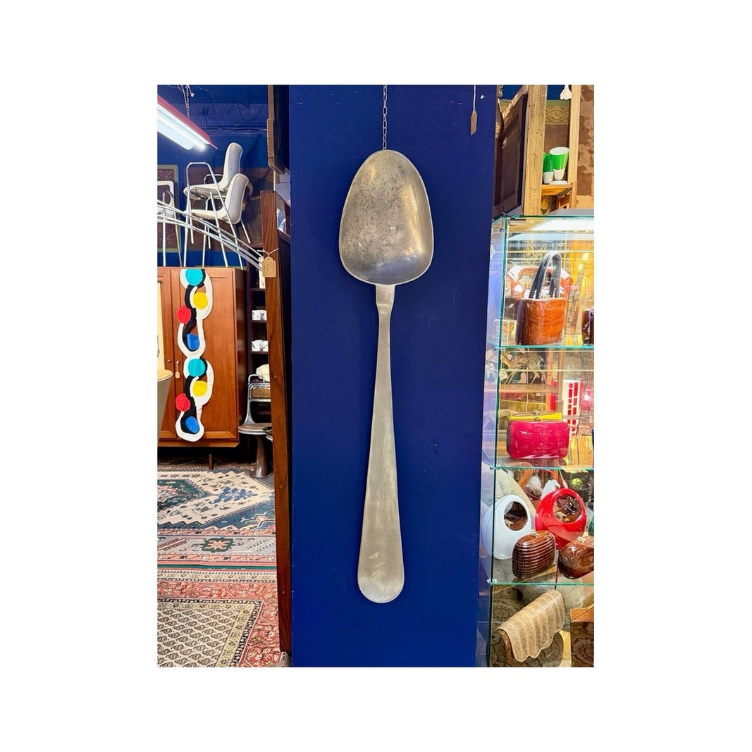 Cuchara decorativa de latón colgada en una pared azul de galería vintage
