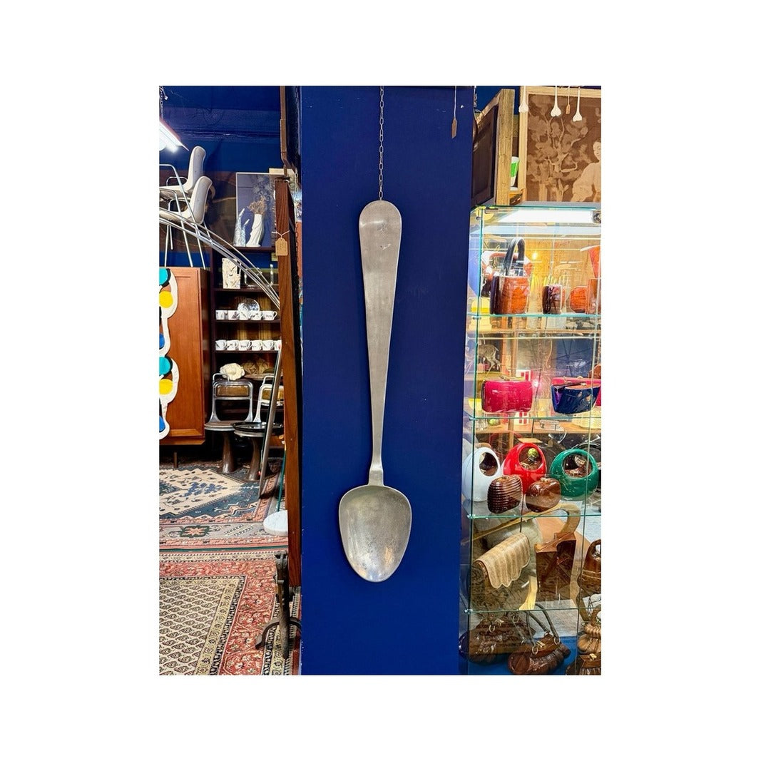 Cuchara escultórica de pared vintage de latón, colgada en una pared azul en una galería