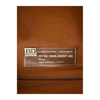 Detalle de la tapicería de tela marrón en el reverso de la butaca, con etiqueta cosida