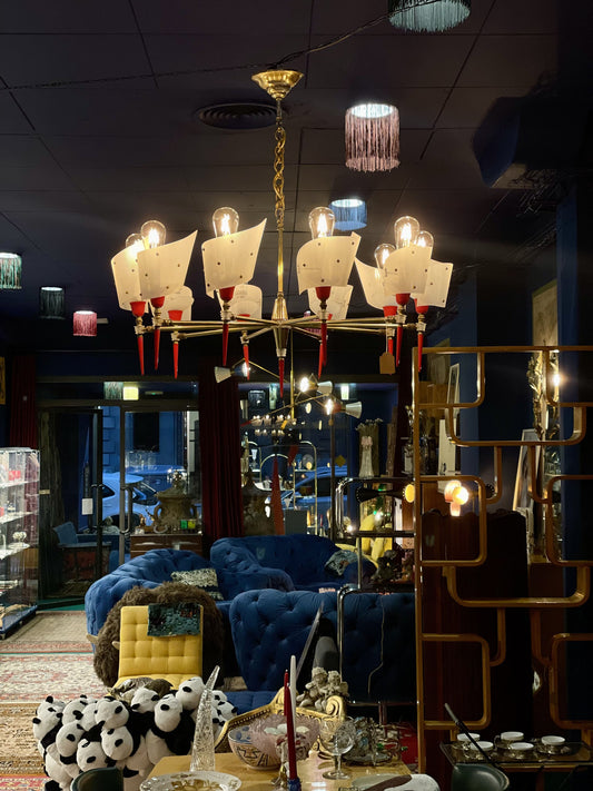 Lámpara colgante mid-century encendida en interior, con brazos radiales de latón y pantallas blancas