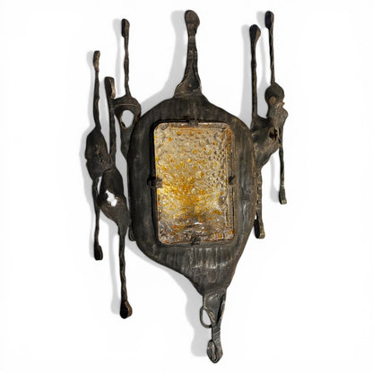 Aplique de pared brutalista de metal oscuro soldado con placa central de cristal ámbar burbujeante y formas orgánicas esculturales.