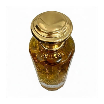 Frasco ámbar facetado de perfume Nina Ricci Phileas 420 ml con tapón dorado, visto desde arriba