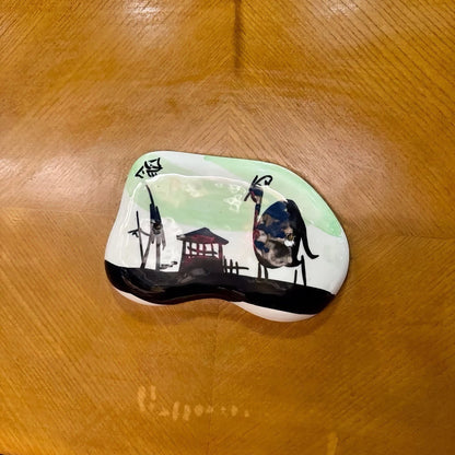 La Basilica Galeria ceramic plaque with graphic iconography of a camel and structure on a light green background.