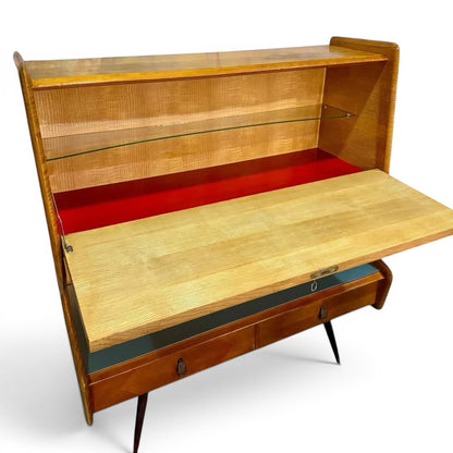 La Basilica Galeria Mid-Century Italian bureau sideboard in honey wood veneer with red lacquer interior, glass shelf, and tapered legs.