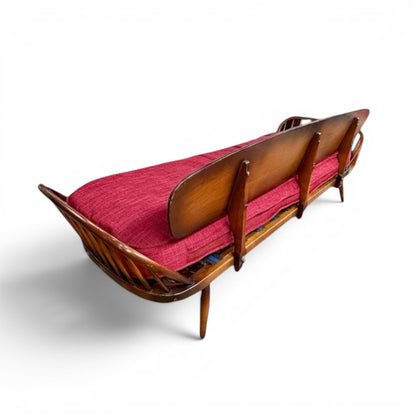 La Basilica Galeria vintage wooden spindle back bench with red upholstered seat and warm wood finish.